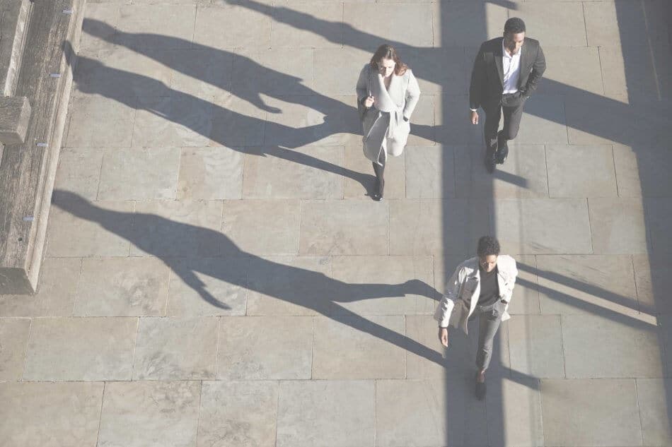 Aerial view of three city workers walking on a sunny urban street, horizontal